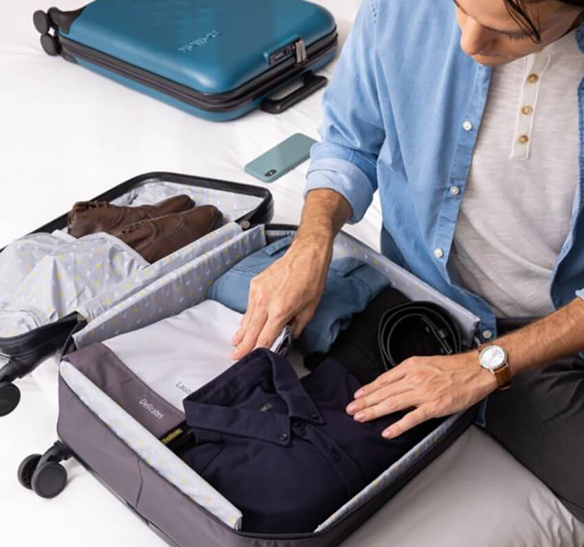 men packing clothes into carry on luggage