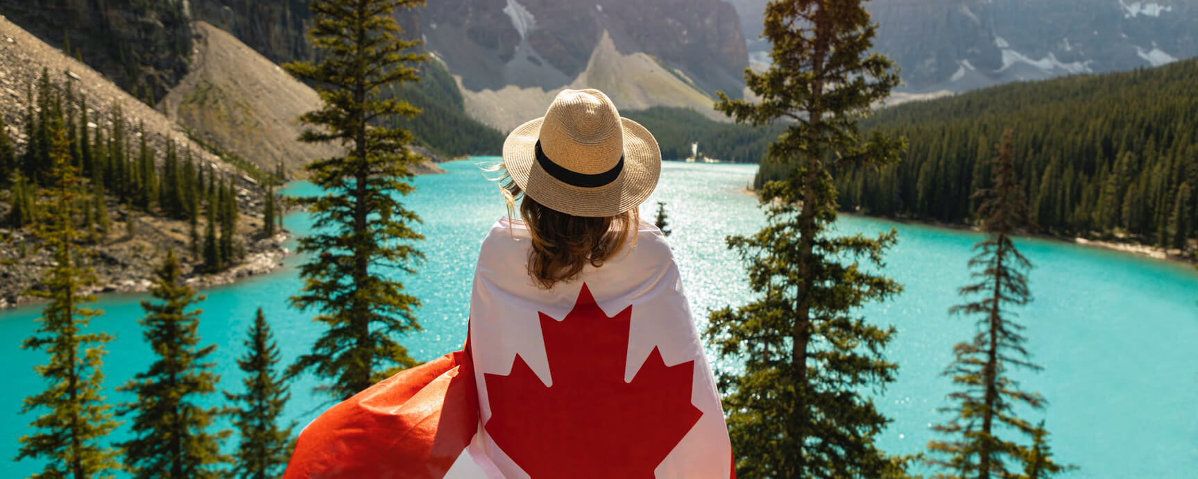 Woman covering Canadian flag facing a lake 