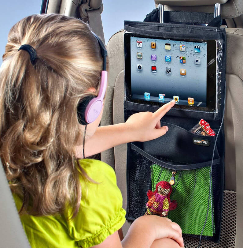 Girl sits in car playing ipad that's inside a car hanger