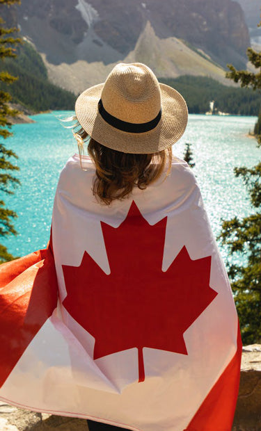 Woman covering Canadian flag facing a lake 